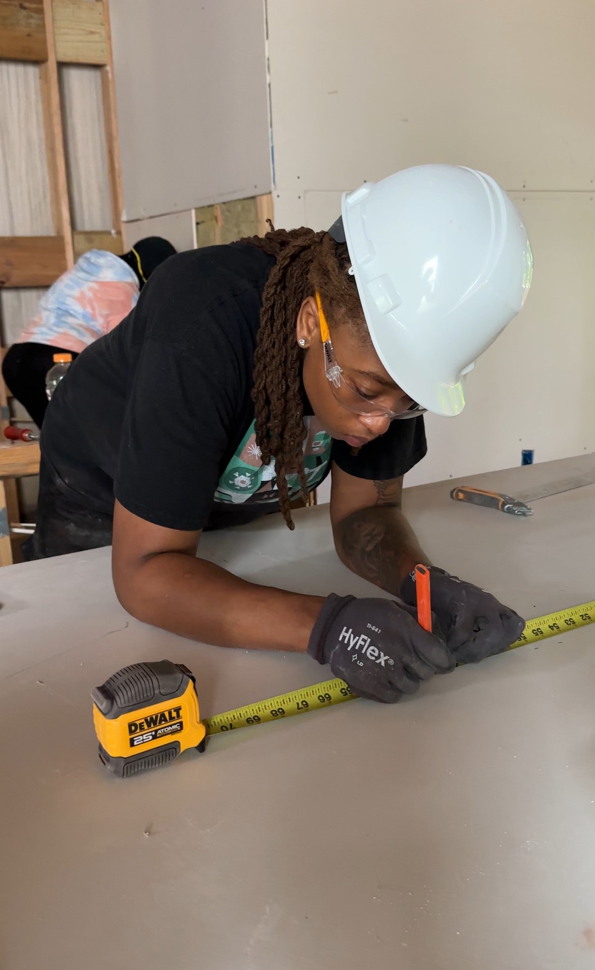 Apprentice measuring drywall on a BEDDIEO project